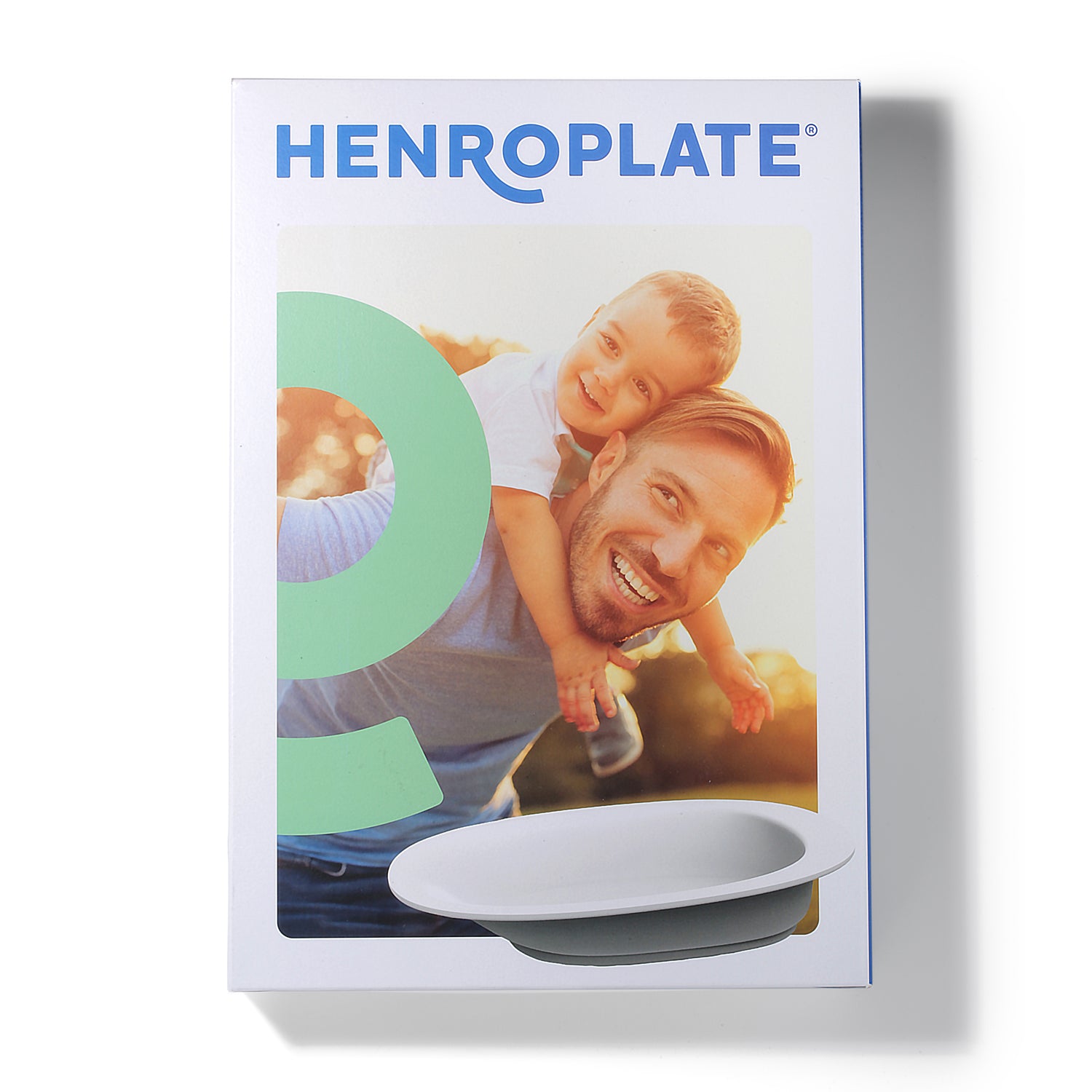 A box labeled "HenroPlate - Adaptive Sloped Plate for Easy One-Handed Eating" by Assistive Tech shows a smiling man giving a young boy a piggyback ride with sunlight behind them, and displays an image of the white adaptive plate at the bottom.