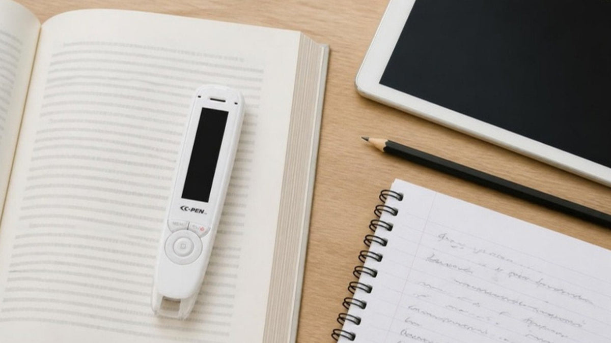 C-Pen Reader 2 on a book beside handwritten notes and a tablet