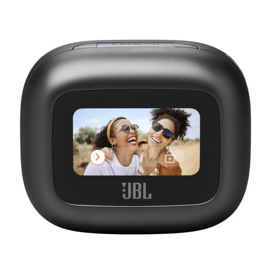 A black JBL portable speaker sits next to the new JBL Live Beam 3 In-Ear Headphones with Noise Cancellation in Black, delivering immersive Hi-Res Audio, as a screen displays two smiling women wearing sunglasses outdoors.