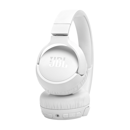 White JBL Tune 670 Noise Cancelling Headphones (On-Ear) by JBL shown with a padded headband and ear cups. The left ear cup rests on a surface displaying control buttons, ports, the JBL logo, and features adaptive noise cancelling.