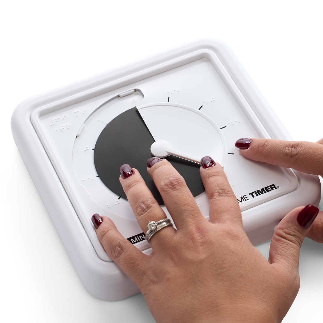 A person with dark red nails sets the Time Timer Braille (8 Inch) [Black Disk] by Time Timer, an assistive timer featuring braille markings. One hand turns the dial while the other rests on its surface.