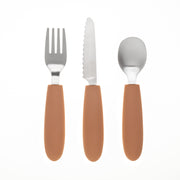 The KiddiKutter Kids Cutlery Set [Peach Fuzz] by KiddiKutter includes a fork, serrated knife, and spoon with brown silicone handles, arranged vertically side by side on a white background.