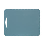The KiddiKutter Silicone Cutting Board (Wavy) [Sky Blue] by KiddiKutter is a rectangular, non-slip silicone board with a wavy edge and left handle slot, shown on a white background.
