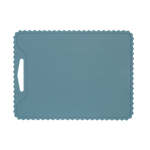 The KiddiKutter Silicone Cutting Board (Wavy) [Sky Blue] by KiddiKutter is a rectangular, non-slip silicone board with a wavy edge and left handle slot, shown on a white background.