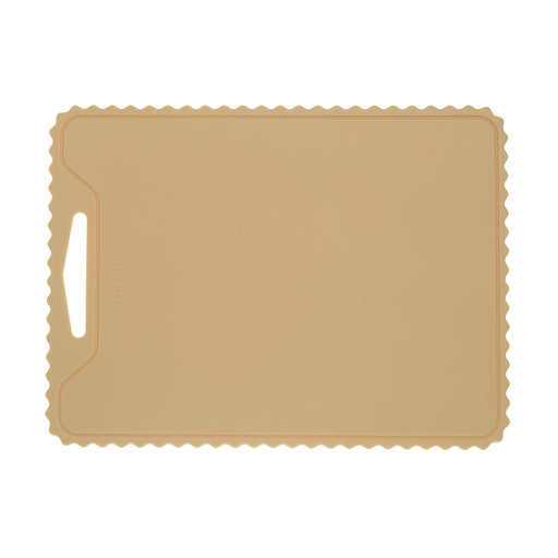 The KiddiKutter Silicone Cutting Board (Wavy) in cream by KiddiKutter features a rectangular, non-slip design with scalloped edges and a handle slot on the left, shown against a white background.