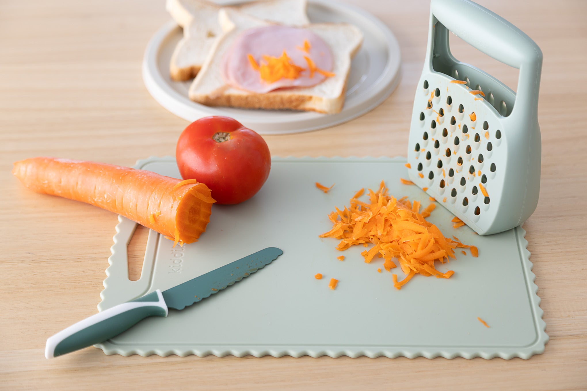 The KiddiKutter Grater by KiddiKutter lets kids safely grate veggies like carrots, making meal prep easy and fun. It's perfect for getting children involved in the kitchen!.