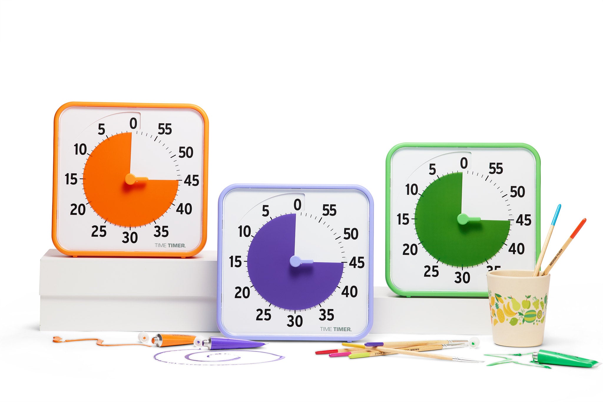 The Time Timer Original (8 inch) Learning Center Classroom Set (Secondary Colour Collection) by Time Timer features three square timers in orange, purple, and green—ideal for classroom time management—shown with markers, pencils, and paintbrushes.