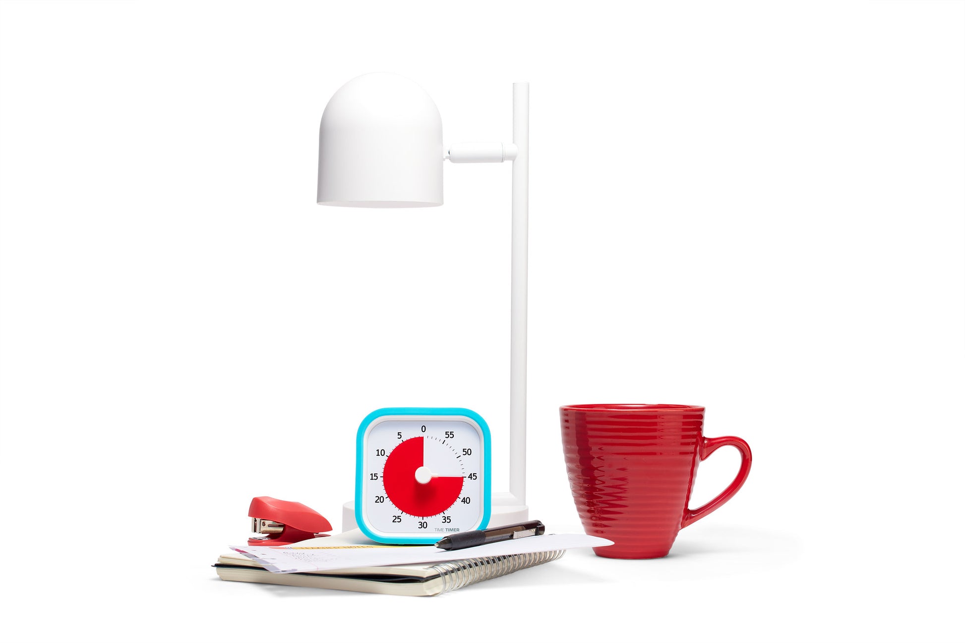 A white desk lamp, red mug, Time Timer MOD [Sky Blue] (Time Timer), red stapler, notepad, pens, and papers are arranged on a white surface against a white background—perfect tools for time management.