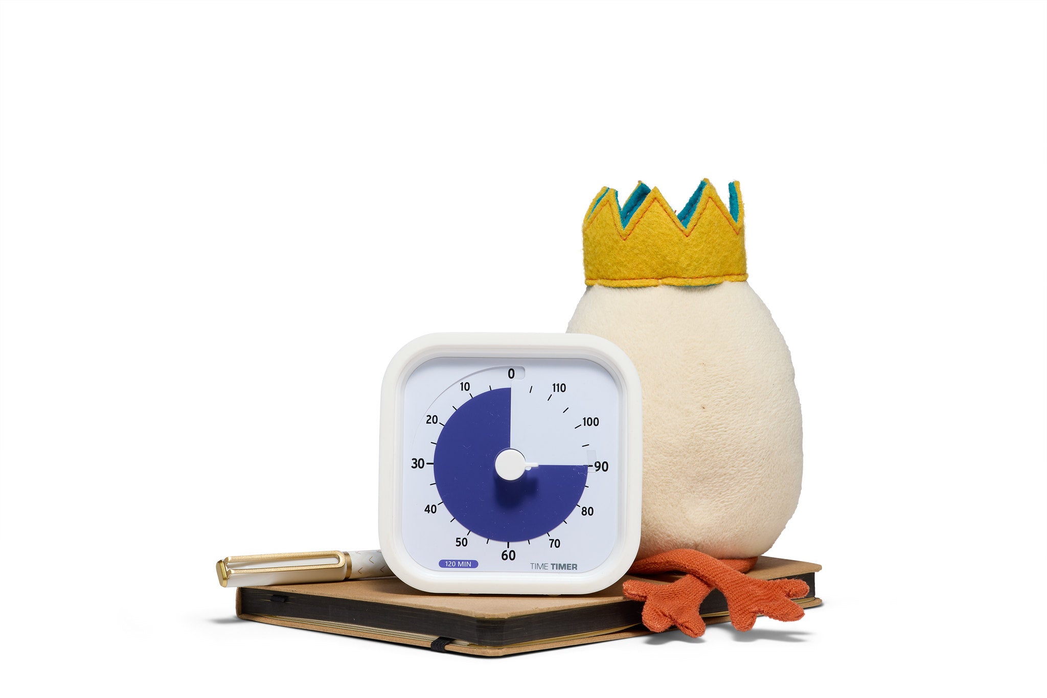 A plush egg with a yellow crown sits on a closed book beside the Time Timer MOD Education (120 min) by Time Timer and a gold pen, all set against a white background—creating an adorable scene for visual time management.