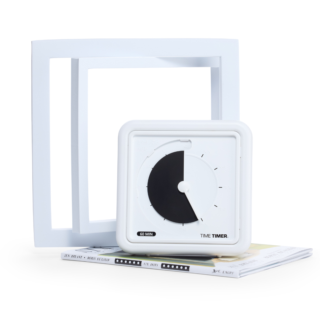 The Time Timer Braille (8 Inch) by Time Timer, with a black disk, rests atop two stacked books before overlapping white square frames—an accessible time management aid designed for tactile and visual assistance.