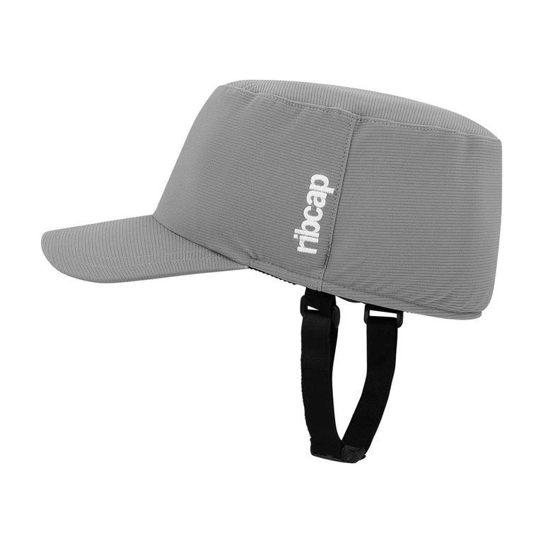The Ribcap Bowie Cap Protective Helmet [Grey] by Ribcap features a short brim, black adjustable chin straps, and "ribcap" printed in white on the side, offering discreet head protection.