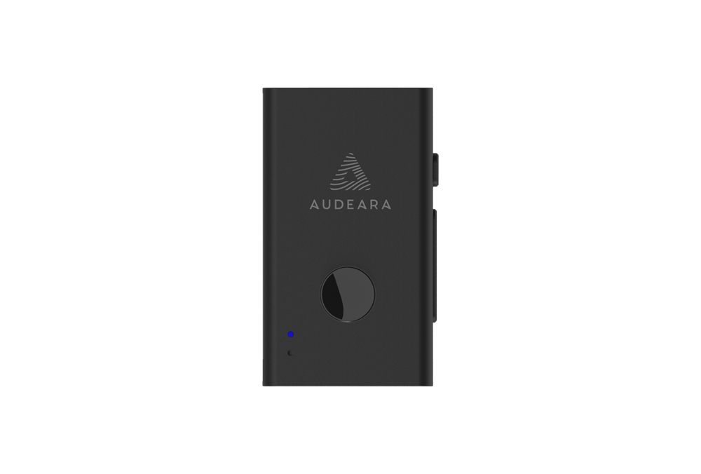 The Audeara Audio Transceiver & Lapel Microphone – Auracast™ & Bluetooth® is a black rectangular device with a circular button, small LED indicator, side buttons, and the Audeara logo on the front, set against a plain white background.