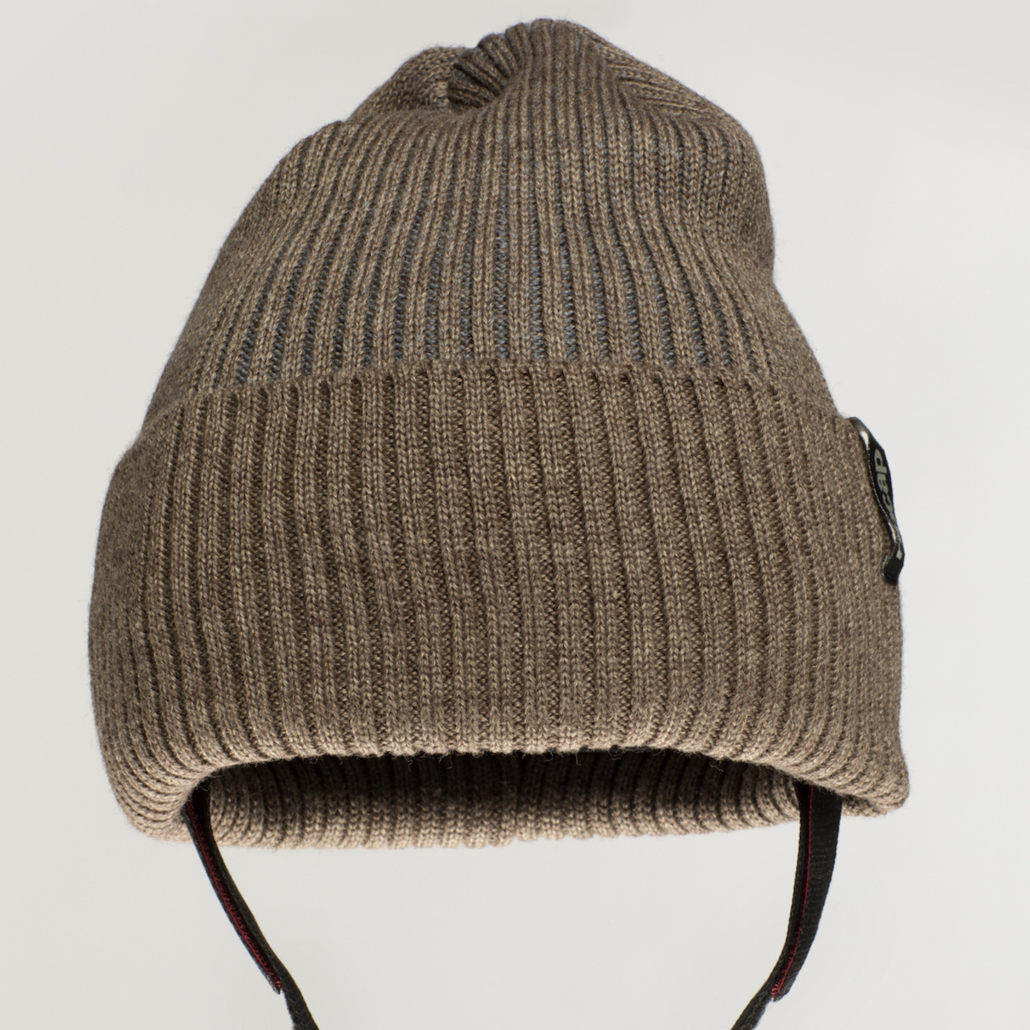 The Ribcap Iggy Beanie Protective Helmet in brown by Ribcap is a ribbed knit beanie with ear flaps and two black hanging straps, designed for protection and comfort, shown against a plain light background.