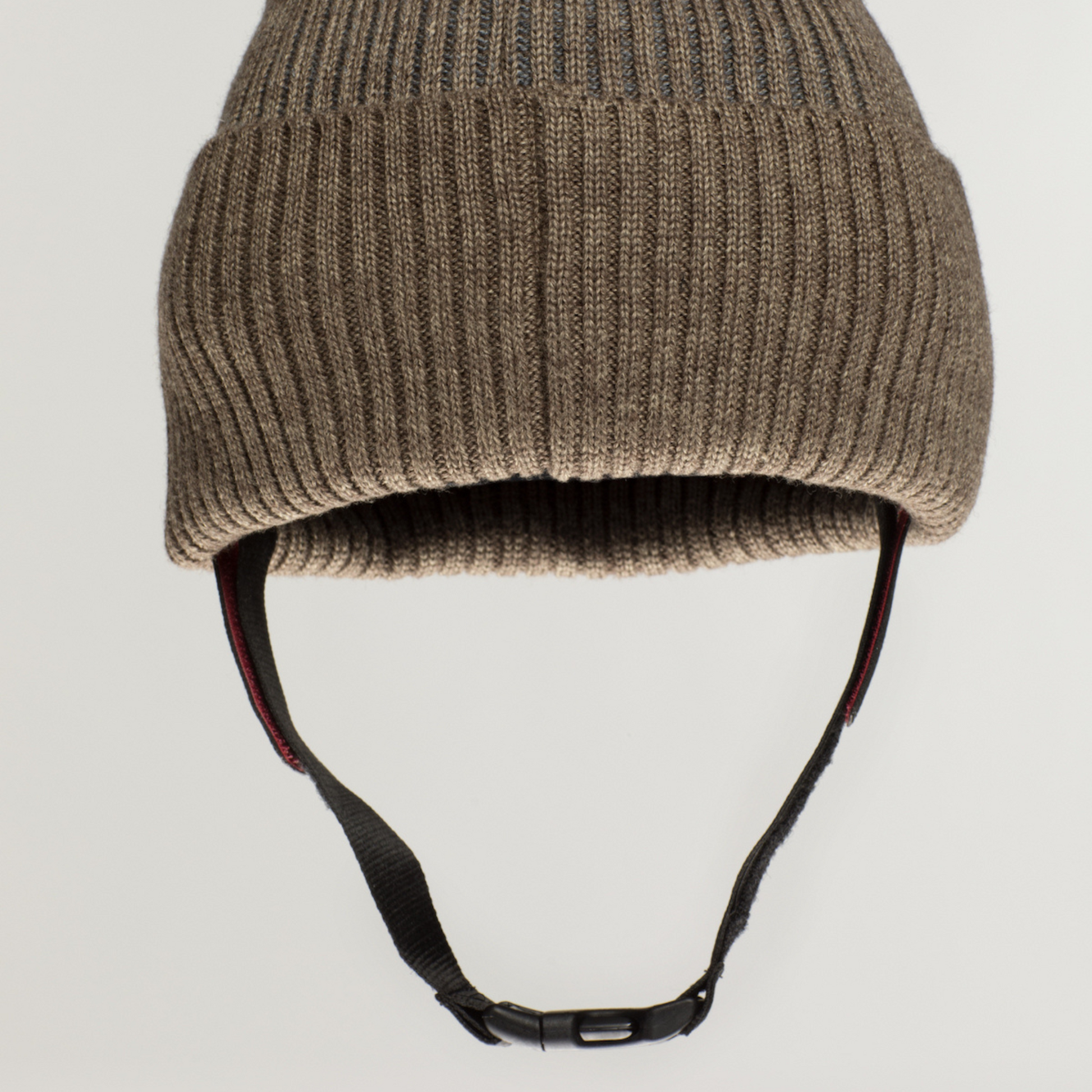 The Ribcap Iggy Beanie Protective Helmet [Brown] by Ribcap is a brown knit beanie styled as a soft helmet with a black adjustable chin strap, shown against a plain light background.