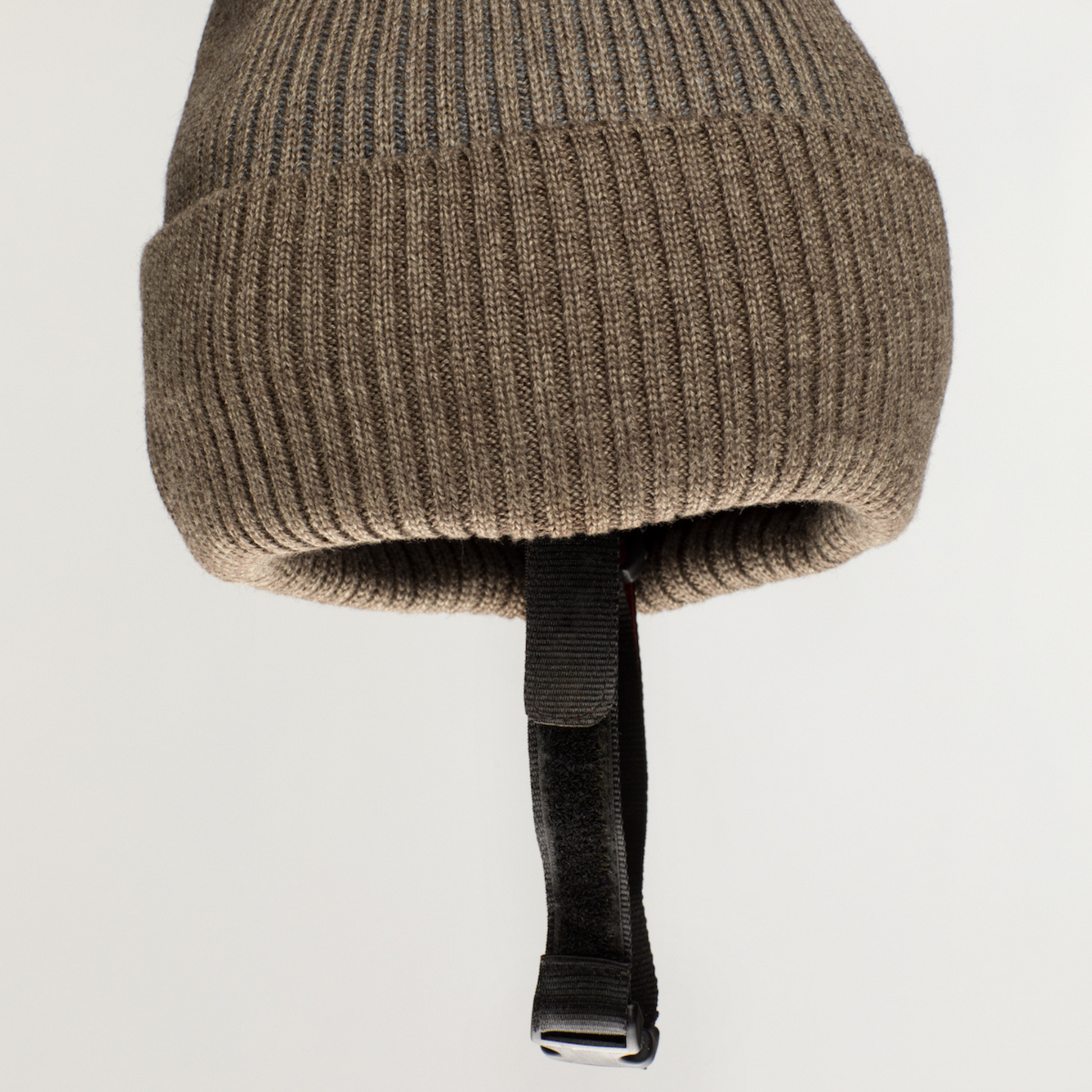 The Ribcap Iggy Beanie Protective Helmet [Brown] by Ribcap is a soft, brown ribbed knit beanie with a folded cuff and an adjustable black chin strap with a plastic buckle, shown against a plain light background.