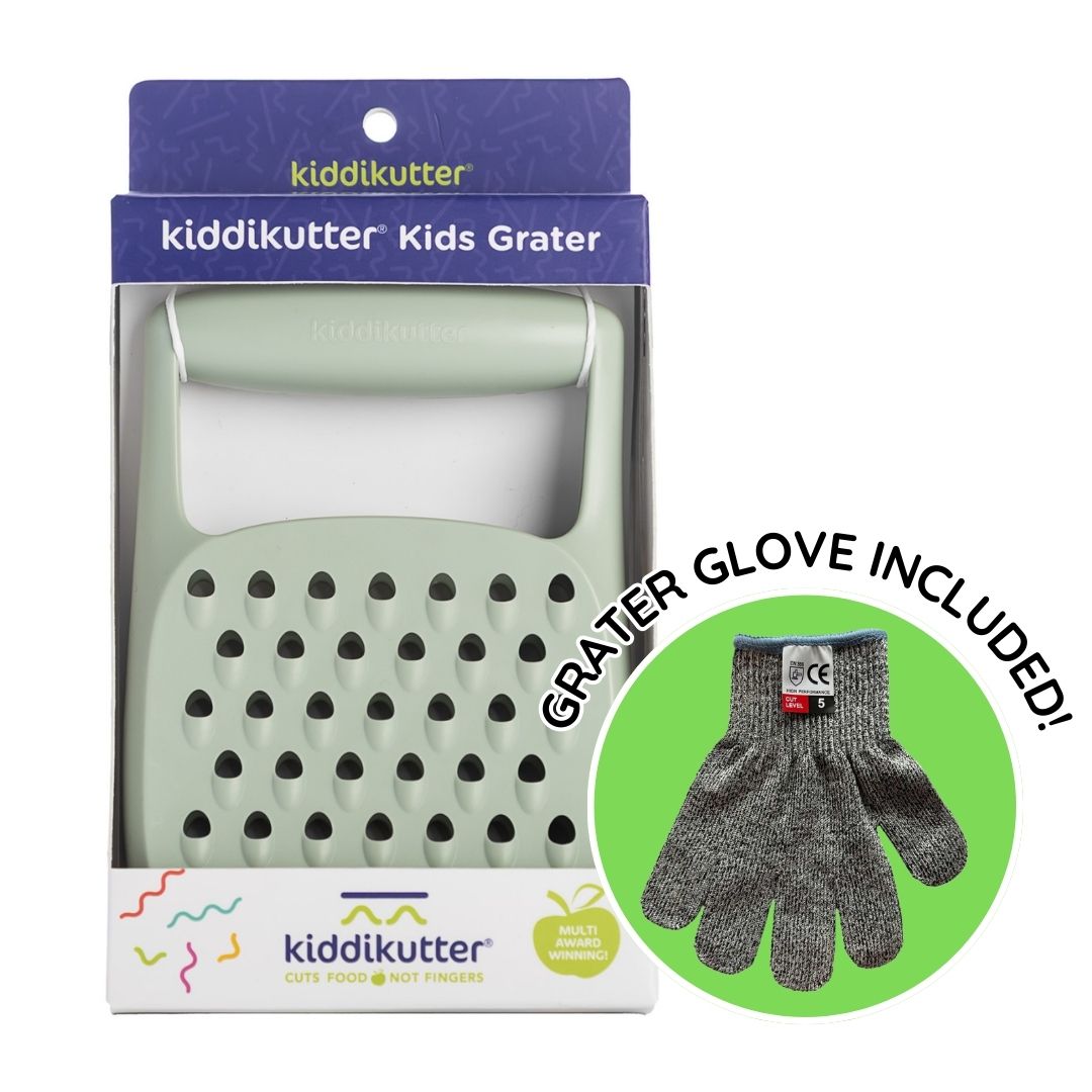 The KiddiKutter Grater by KiddiKutter features a light green handle, large grating holes, and comes in packaging with a circular inset showing a grey safety glove. “GRATER GLOVE INCLUDED!”—a safe kitchen tool for kids.