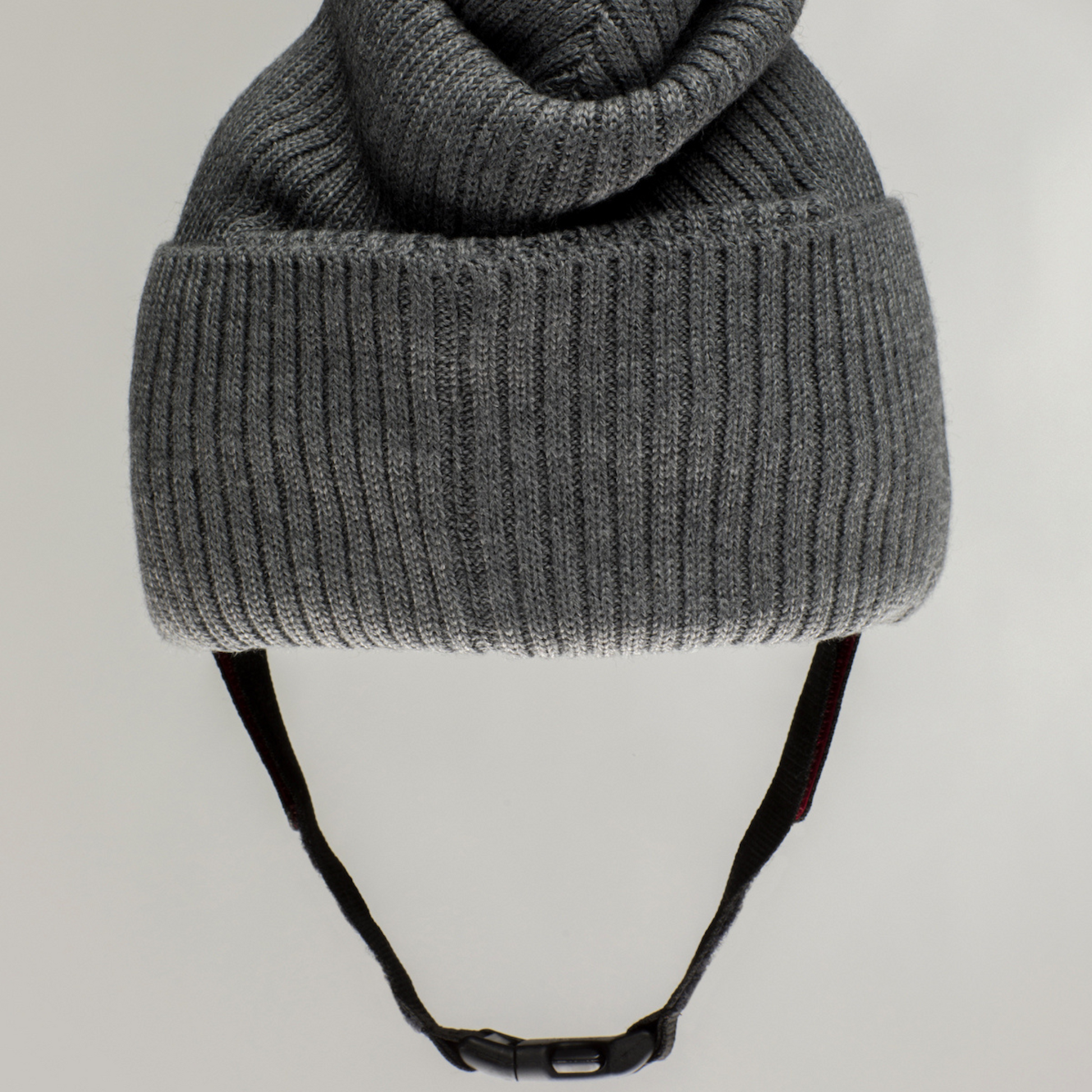 The Ribcap Lenny Beanie Protective Helmet [Grey] by Ribcap is a gray knitted beanie for adults, featuring a folded brim and adjustable black chin strap for stylish comfort and soft head protection.