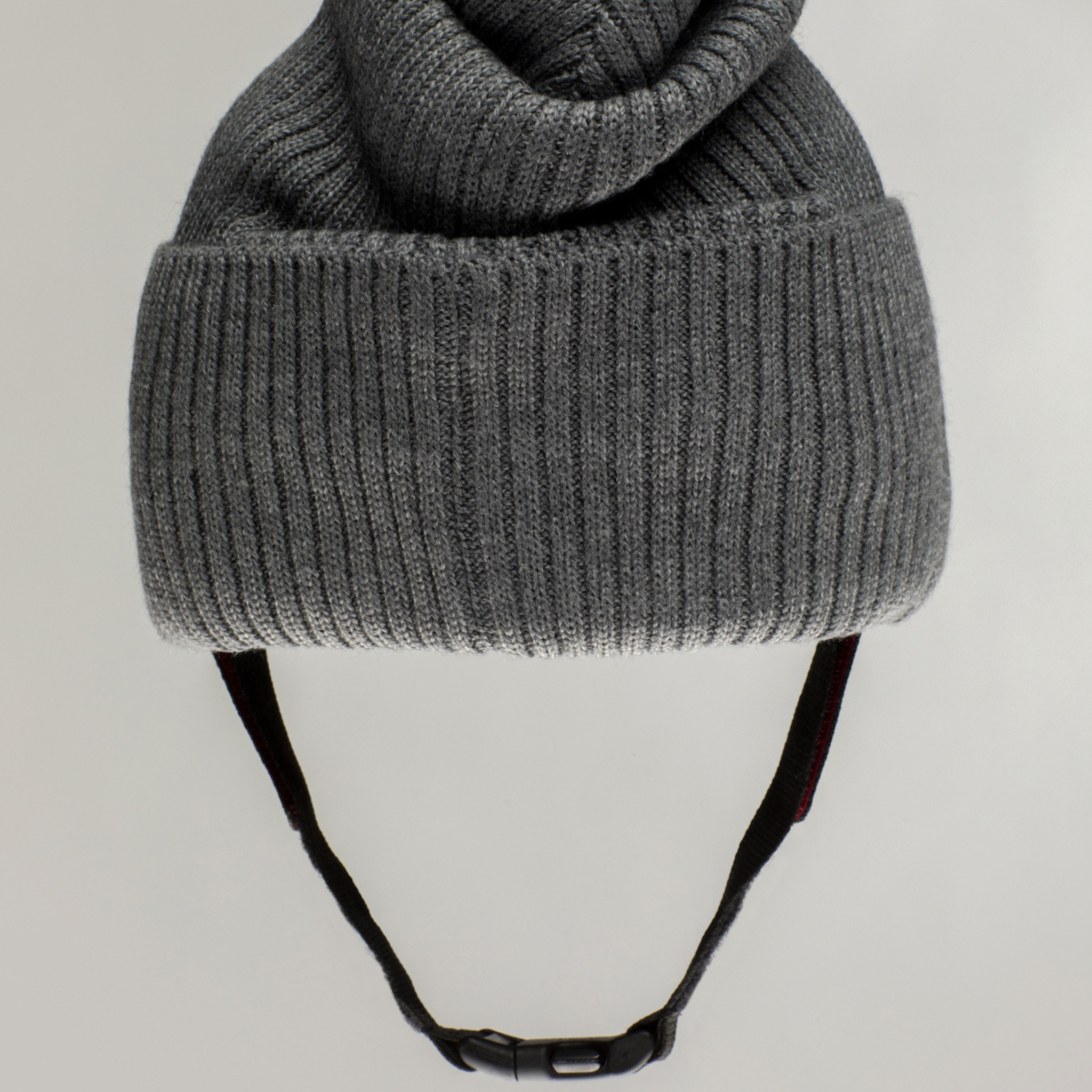 The Ribcap Lenny Beanie Protective Helmet [Grey] by Ribcap is a gray knitted beanie for adults, featuring a folded brim and adjustable black chin strap for stylish comfort and soft head protection.