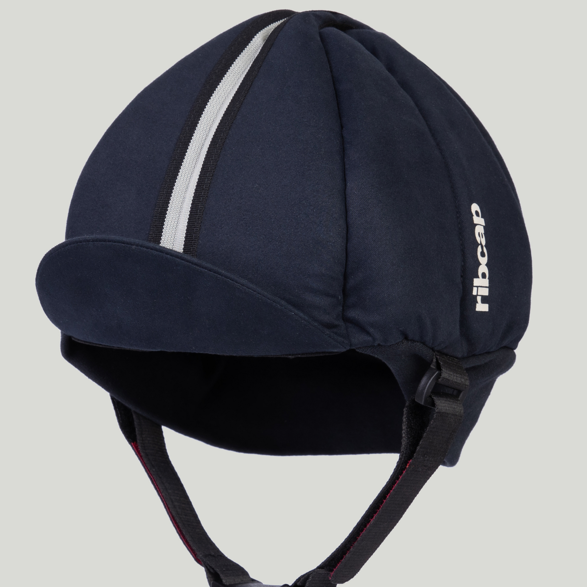The Ribcap Hardy Protective Helmet Cap in Navy Blue features a soft, dark blue shell, small brim, central reflective stripe, black chin straps, and the Ribcap logo—designed for comfortable, discreet head protection for epilepsy or similar needs.