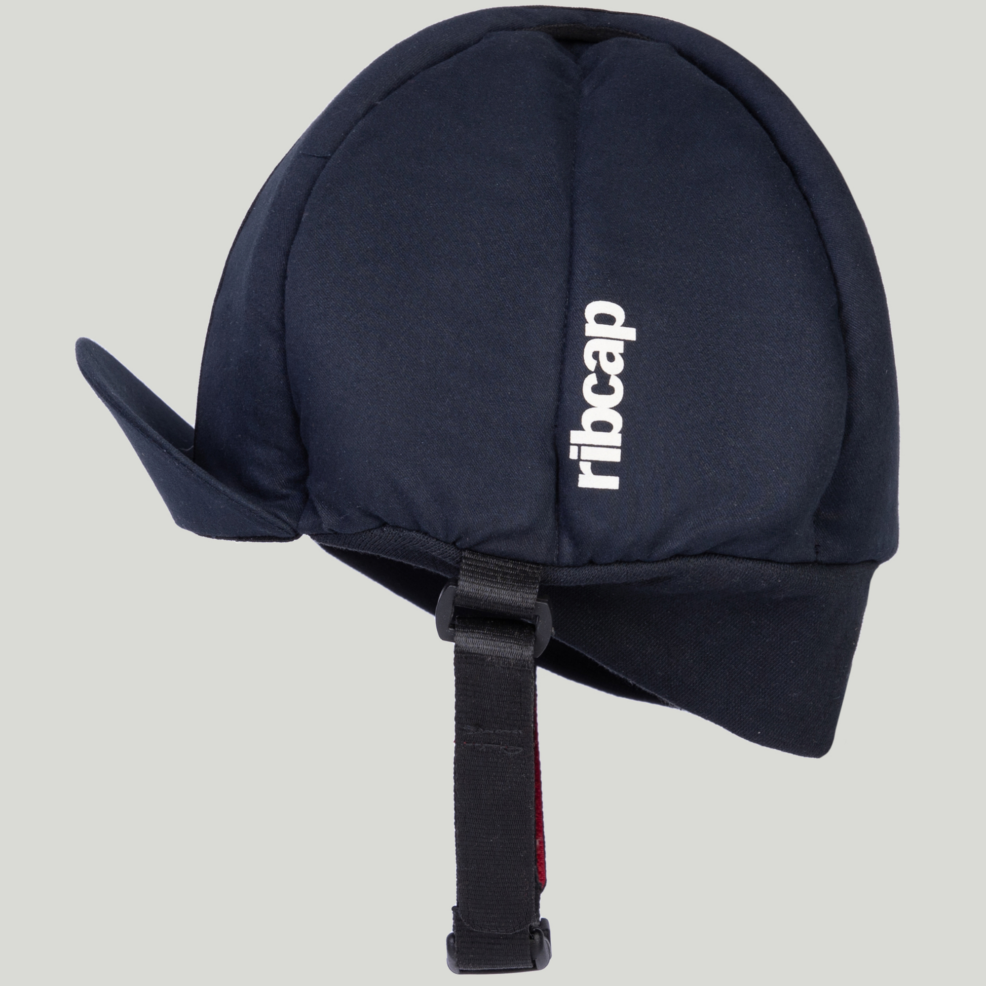 A navy blue Ribcap Hardy Protective Helmet Cap by Ribcap, featuring two side flaps, an adjustable buckle chin strap, and "ribcap" in white on the side, shown against a light gray background.