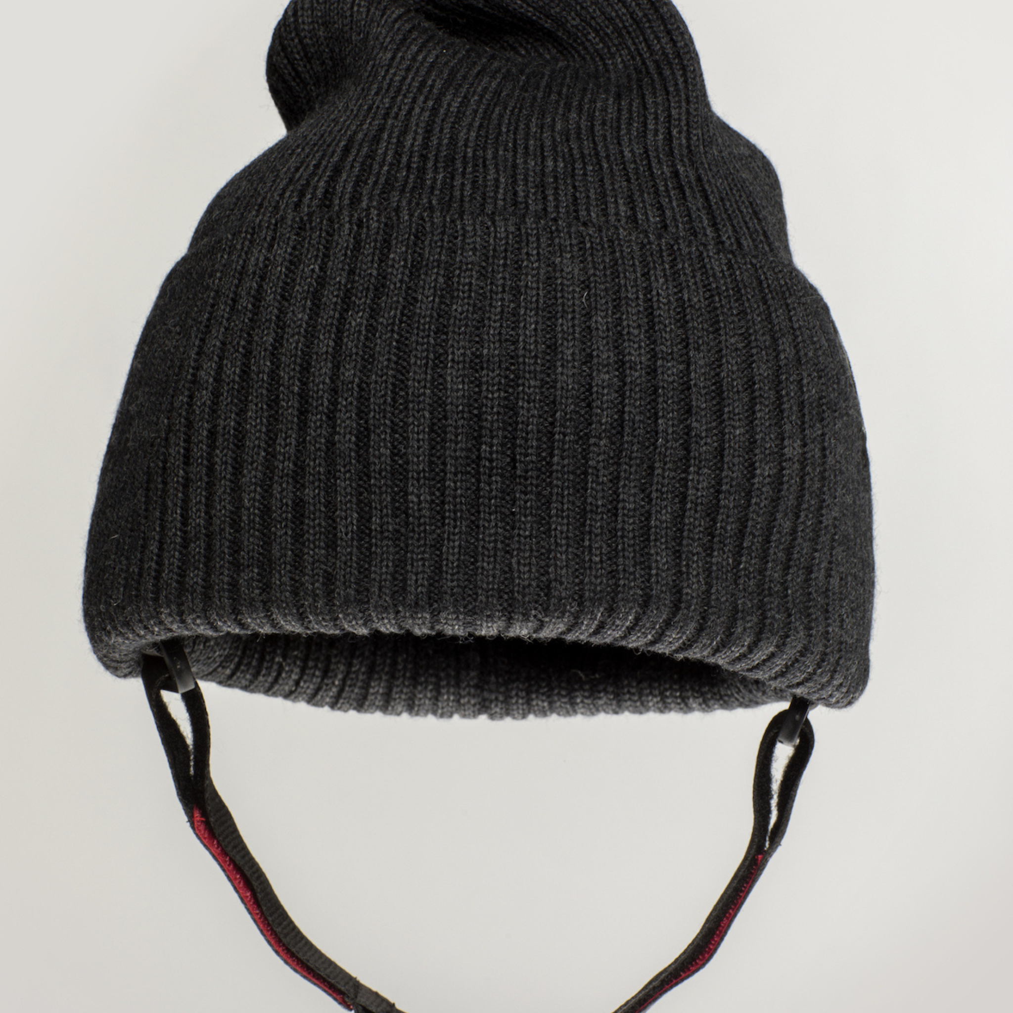 The Ribcap Lenny Beanie Protective Helmet [Anthracite] by Ribcap is a dark gray ribbed knit beanie with ear flaps and adjustable chin straps, designed for soft protection and shown against a plain light background.
