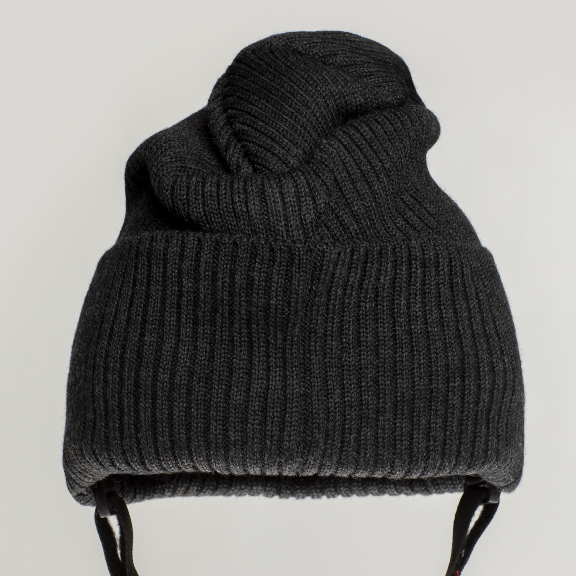 The Ribcap Lenny Beanie Protective Helmet [Anthracite] by Ribcap is a dark gray, thickly ribbed knit beanie with ear flaps and black straps, resembling a soft protective helmet, shown against a plain light background.