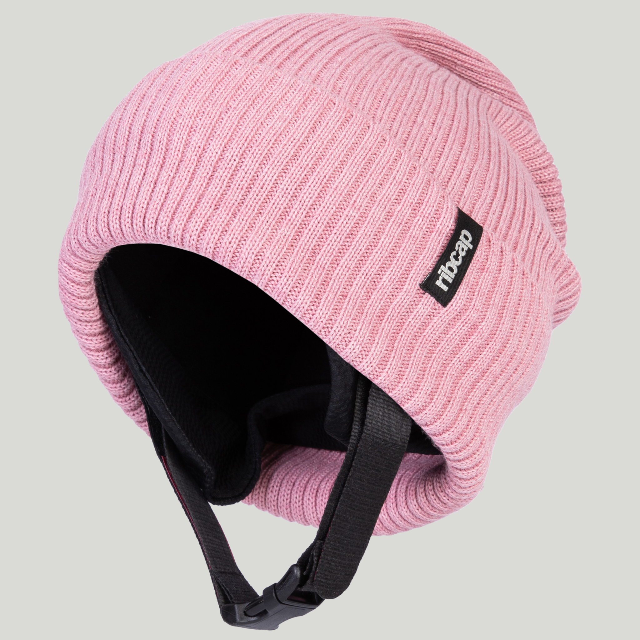 The Ribcap Lenny Beanie Protective Helmet [Rose] by Ribcap is a pink ribbed knit helmet with black ear covers, chin strap, and logo tag—ideal as a protective medical helmet for adults with autism.