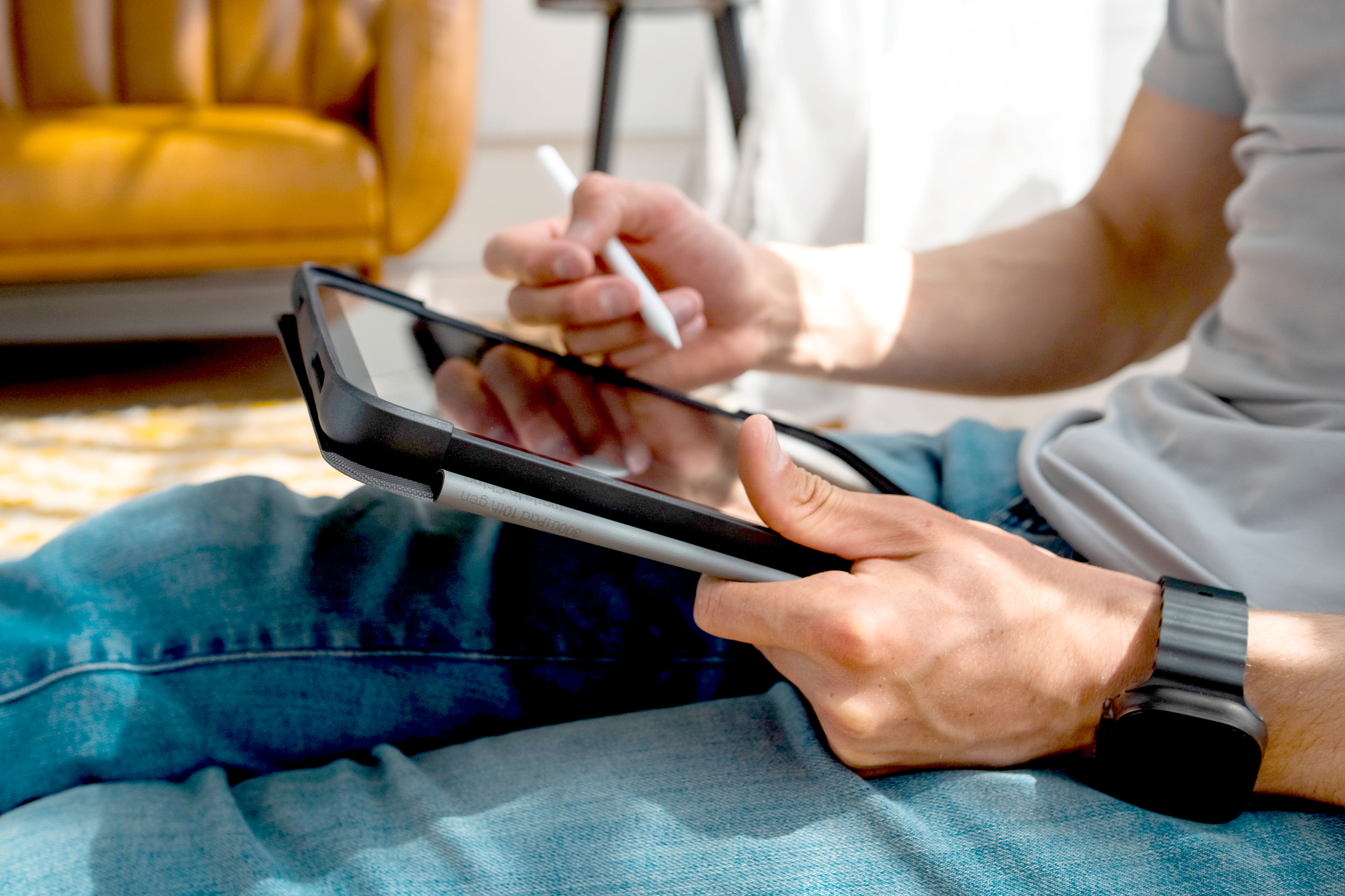 Person using a tablet and pen on a couch