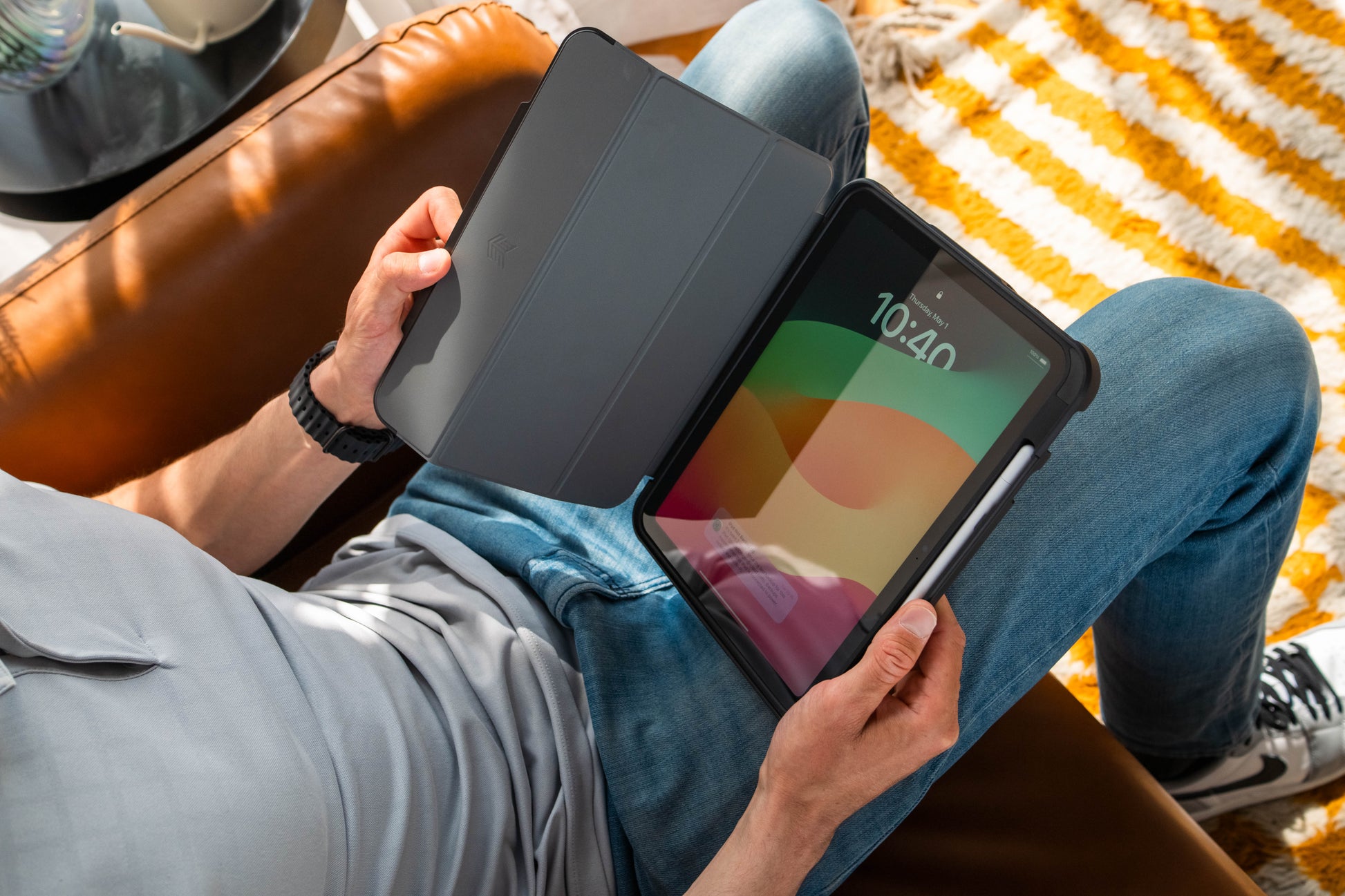 Person holding a tablet with a colorful display on a striped blanket