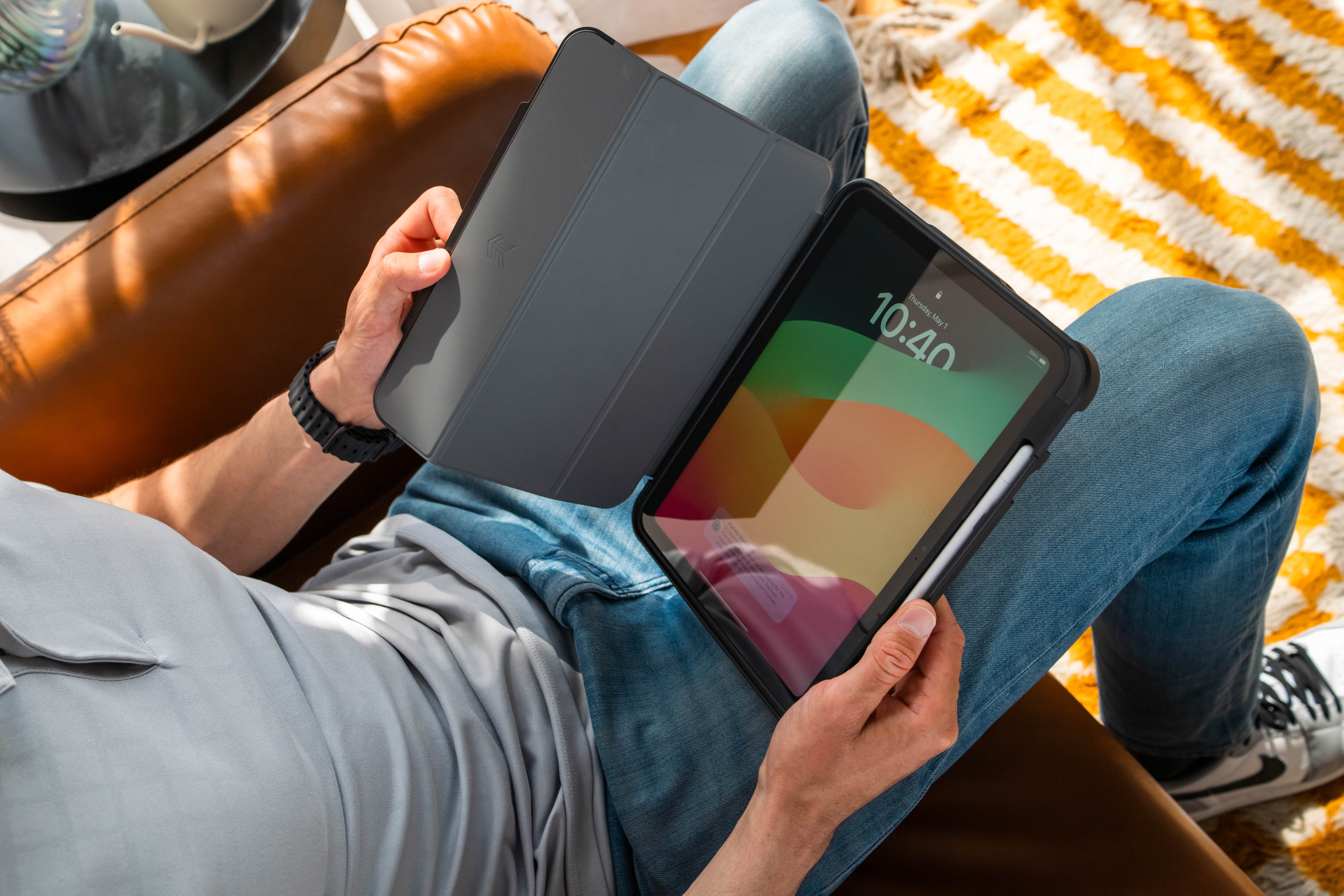 Person holding a tablet with a colorful display on a striped blanket