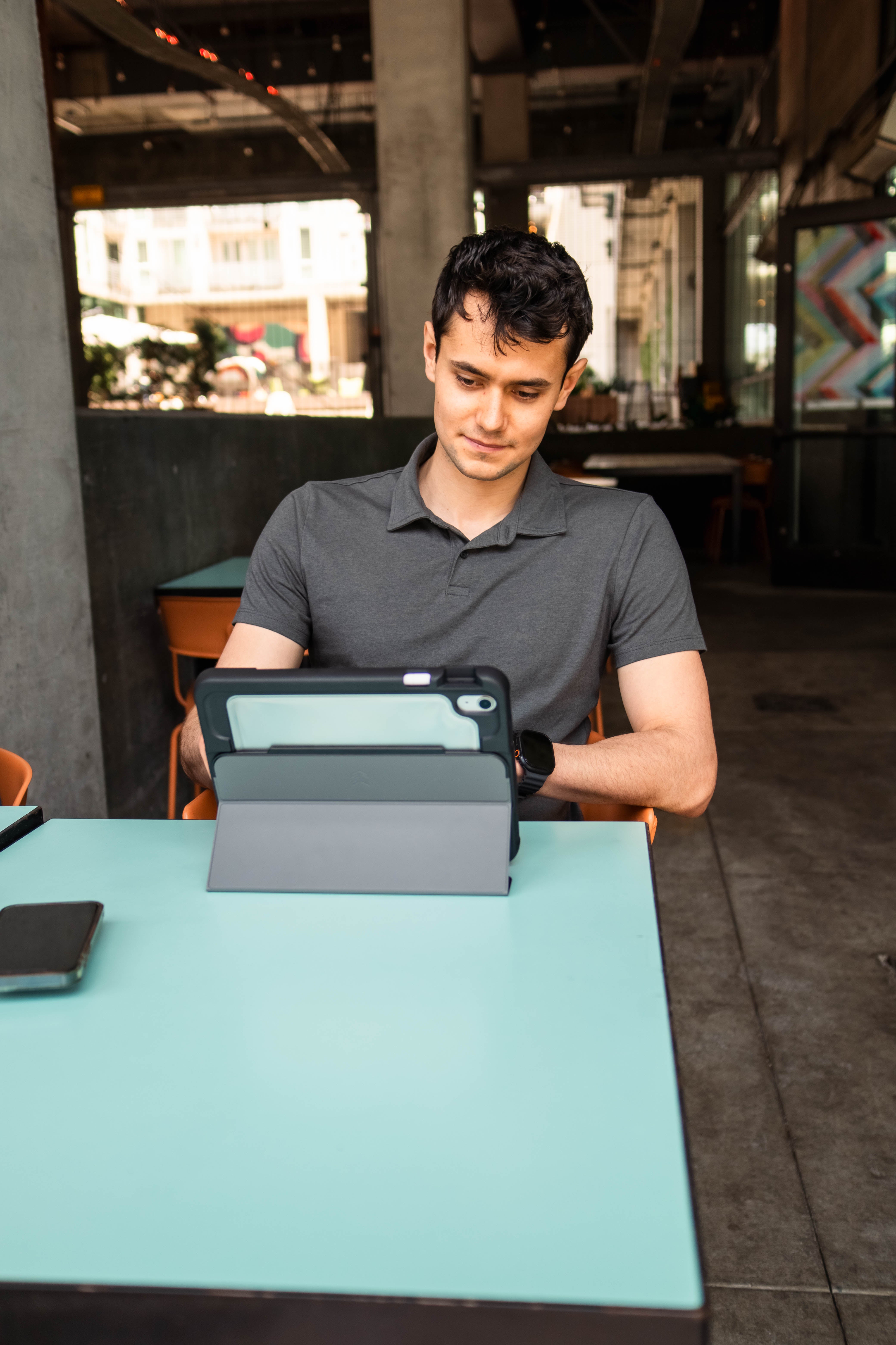 Man using a tablet at a table in an urban setting