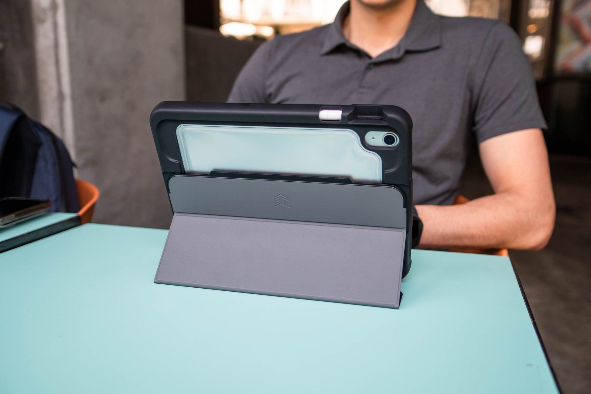 Person holding a tablet case on a table with a blurred background