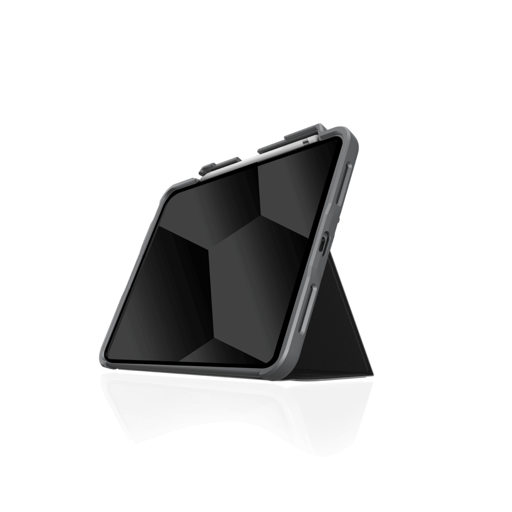 An iPad in an STM Dux Plus Case [Black] (for iPad A16/10th/11th Gen) stands upright in landscape mode, propped by its foldable cover with military drop protection, set against a plain white background.