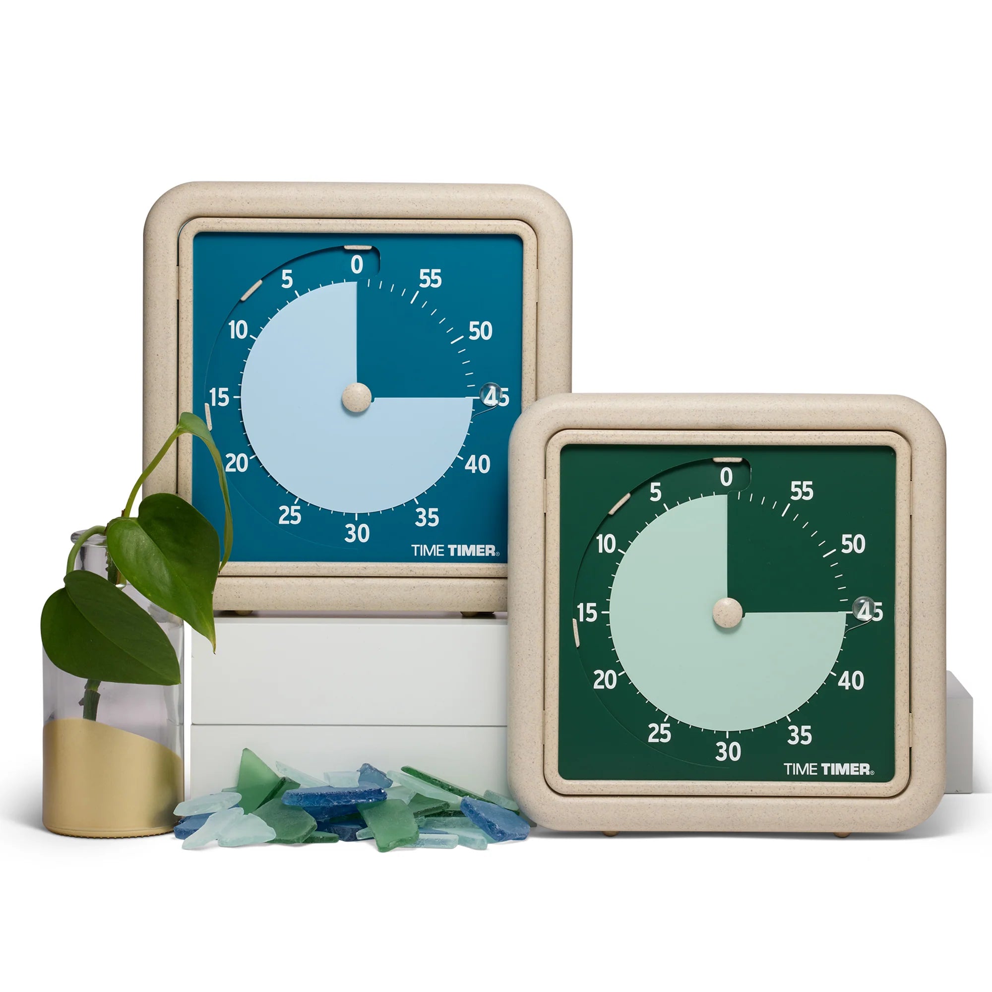 Two Time Timer Retro Eco (8 Inch) [Water/Blue] visual timers by Time Timer, one blue and one green, display different countdowns on a white surface with a gold vase and blue and green sea glass next to them.