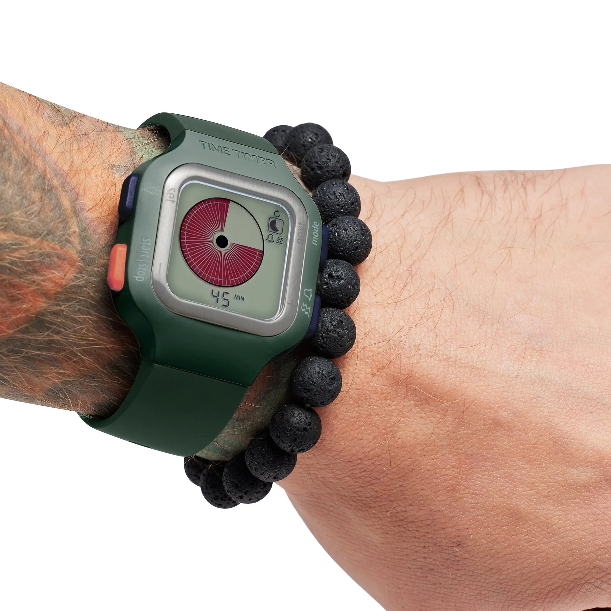 A tattooed wrist wearing a Time Timer Watch (Large/Adult) by Time Timer, featuring a colorful display in dark green, is paired with a black beaded bracelet against a white background.