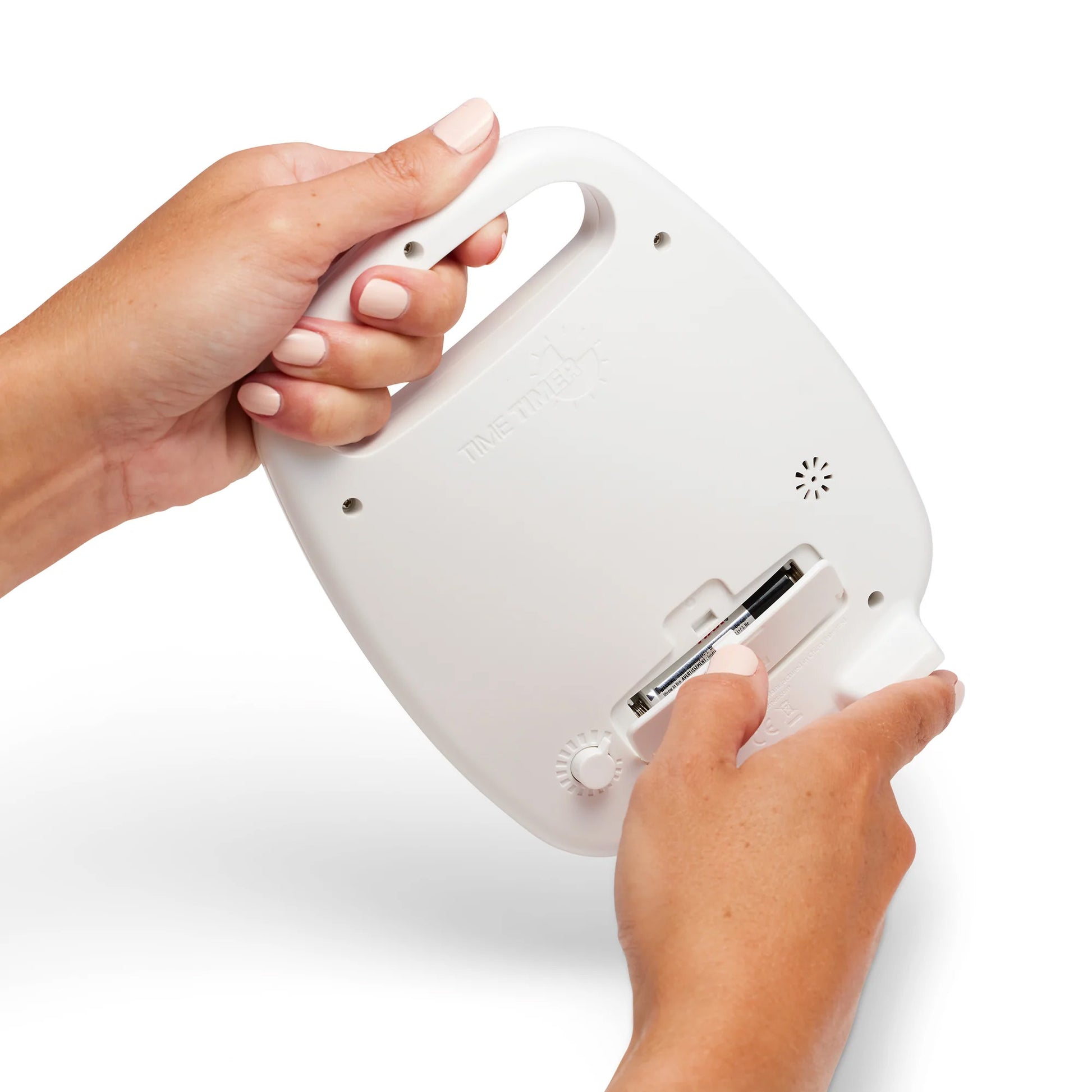 Two hands insert AA batteries into the back of a white Time Timer Plus (60 min) by Time Timer, featuring a handle, speaker grill, and small dial—an ideal tool for effective time management.