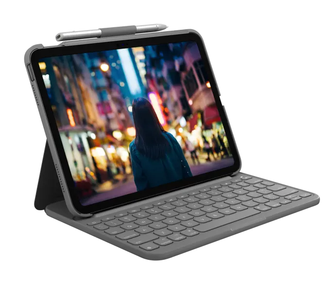An iPad in a Logitech Slim Folio Keyboard Case, paired with a stylus, displays an image of a person standing on a brightly lit city street at night, viewed from behind.