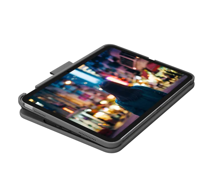 An iPad (A16/10th/11th Gen) in a black Logitech Slim Folio Keyboard Case rests on a light surface, screen showing a blurred person in front of colorful city lights at night.